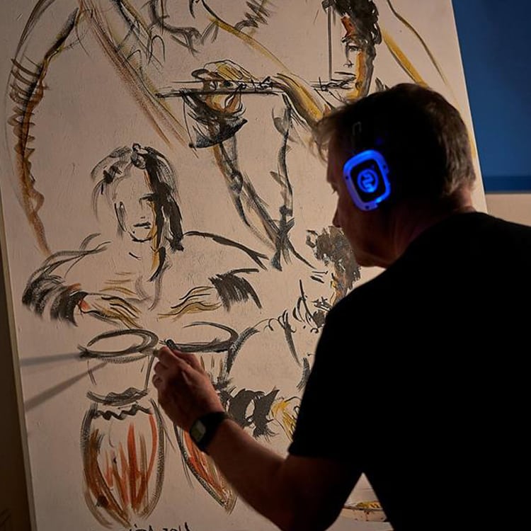 live-painting Καλλιτέχνης ζωγραφίζει live φορώντας μπλε ασύρματα ακουστικά LED
