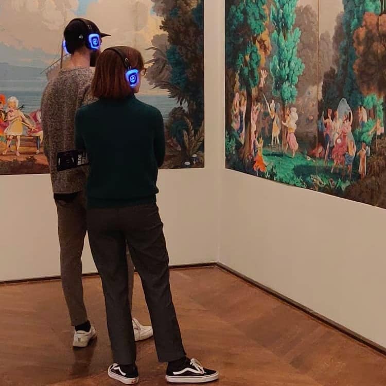 Palazzo del Louvre Επισκέπτες με ασύρματα ακουστικά μπροστά σε πίνακες στο Λούβρο