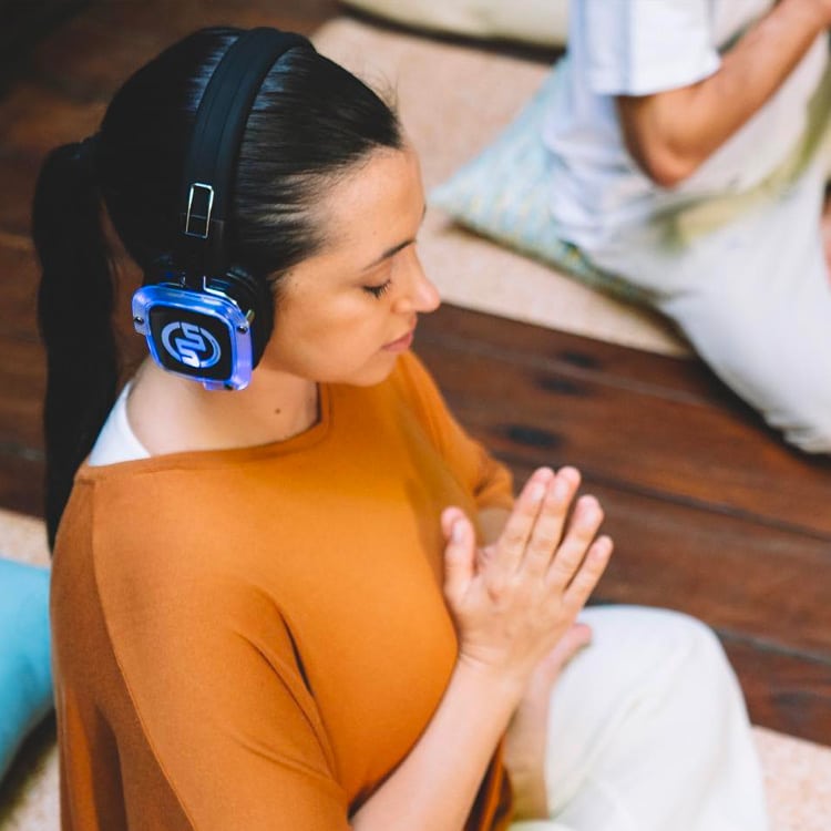 newyogi Γυναίκα διαλογίζεται με ασύρματα ακουστικά σε μάθημα Silent Yoga