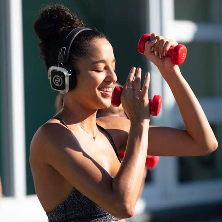 pilates Νεαρή γυναίκα προπονείται με αλτήρες φορώντας ασύρματα ακουστικά