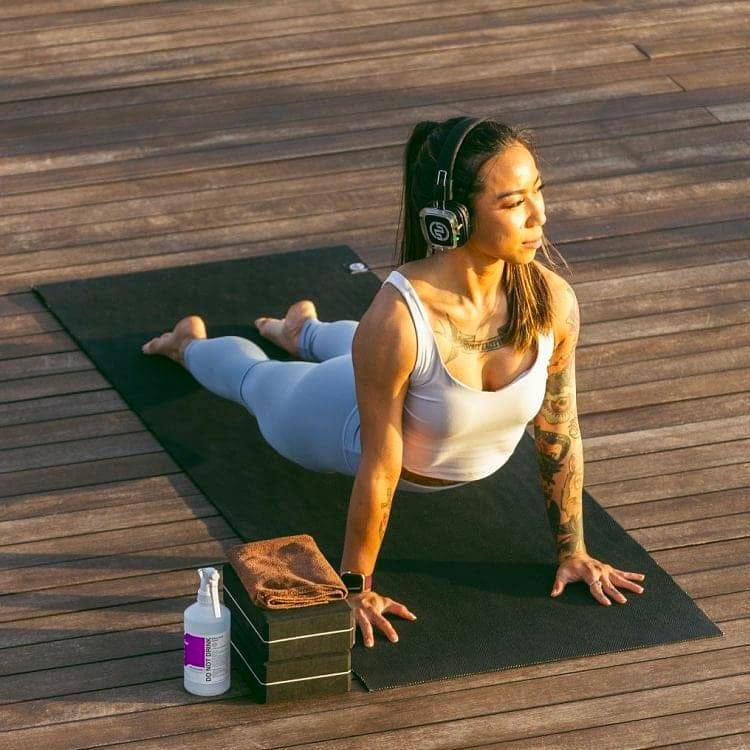 sun-yoga Στάση yoga κόμπρα σε ξύλινη εξέδρα με ασύρματα ακουστικά