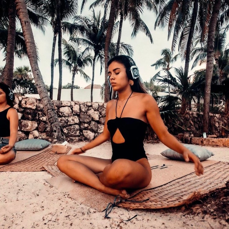 yoga-meditation Διαλογισμός yoga σε παραλία ανάμεσα σε φοίνικες με ασύρματα ακουστικά